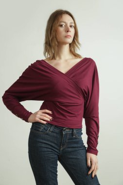 Stüdyoda, organik pamuktan yapılmış bordo gömlek giyen genç bir kadın modelin fotoğrafı. Rahat sürdürülebilir moda.