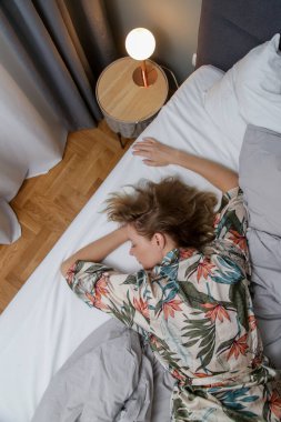 Büyük bir yatakta buruşuk çarşafların arasında genç esmer