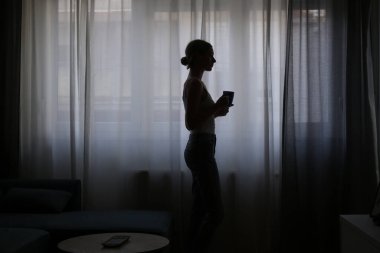 Pencerenin yanında kahve içen kadın.