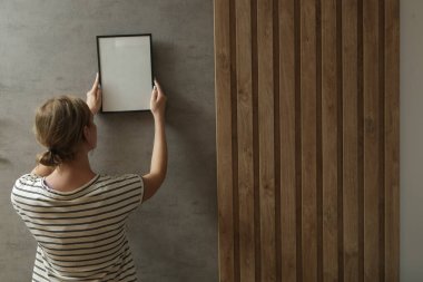 Yeni evin duvarlarında resim çerçeveleri düzenleyen kadın, ev geliştirme konseptini bozuyor.