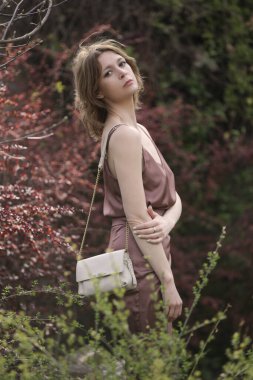 Kamu parkında kahverengi ipekli kadın modelin açık hava portresi.