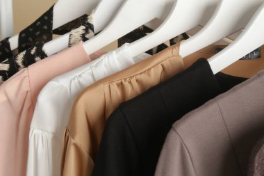 Kadın kıyafetleri. Moda atölyesindeki şık ve şık elbiseli elbise askılığı resmini kapat. Minimalist moda blogu kavramı.
