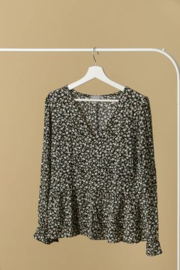 Women's Clothes. Clothes rack with stylish and elegant dark floral blouse on hanger. Good quality timeless fashion piece.