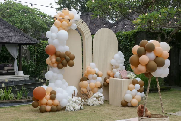 Creative gender neutral baby shower or birthday decoration in the garden. Bohemian style outdoor event set up with balloons. White cream peach caramel balloon arch kit.