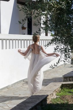 Portrait of the bride in long white wedding dress in the tourist resort, destination wedding concept. Island relaxed boho style bridal fashion.