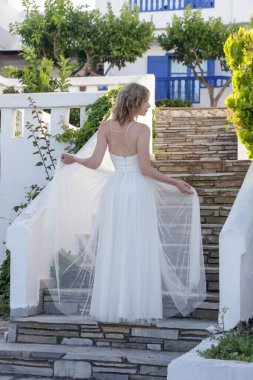 Portrait of the bride in long white wedding dress in the tourist resort, destination wedding concept. Island relaxed boho style bridal fashion.