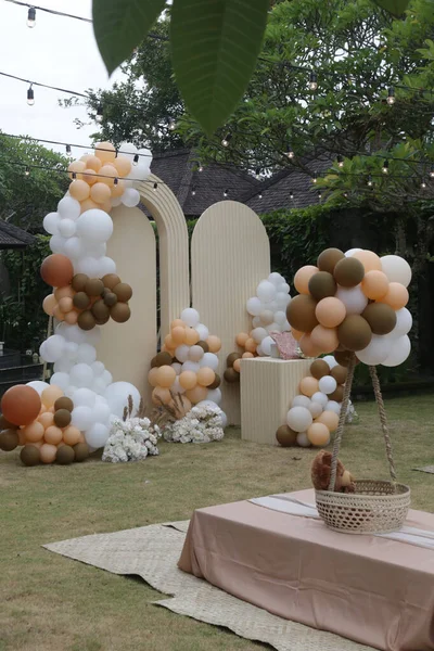 Creative gender neutral baby shower or birthday decoration in the garden. Bohemian style outdoor event set up with balloons. White cream peach caramel balloon arch kit.