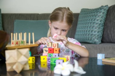 Adorable little girl playing with wooden toys at home