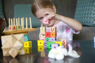 Adorable little girl playing with wooden toys at home