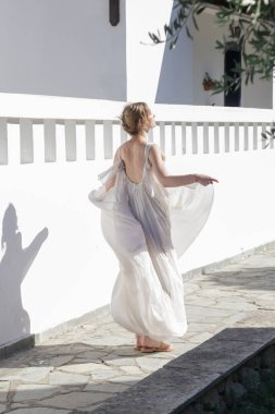 Portrait of the bride in long white wedding dress in the tourist resort, destination wedding concept. Island relaxed boho style bridal fashion.
