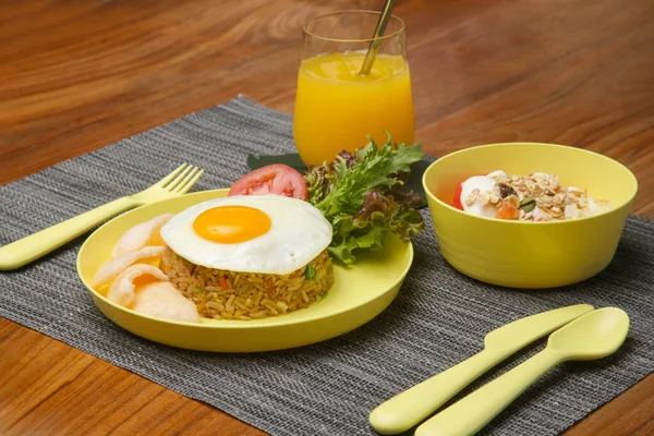 stock image Kids menu - sunny side up, rice, green salad and muesli with yoghurt served on the restaurant table with plastic kids friendly eating utensil.