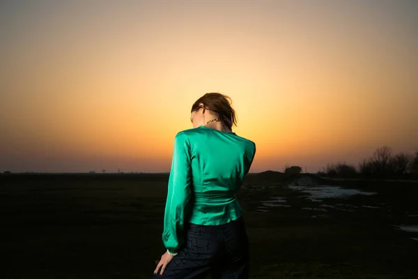 日没時に緑の絹のブラウスとデニムパンツを身に着けている若い素晴らしい女性のファッションスタイルの肖像画 — ストック写真