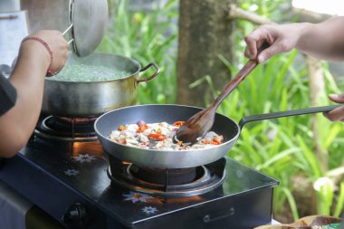 Yetişkin öğrenciler yemek pişirme sınıfında yemek tarifi öğreniyorlar.