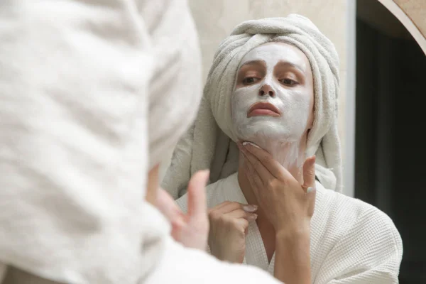 鏡の前で美容フェイスマスクを演じる女性 自宅で美容スキンケアコンセプト — ストック写真