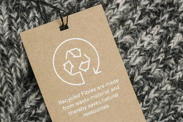 Close up of clothing tag with recycle icon. Recycling products concept. Zero waste, suistainale production, environment care and reuse concept.