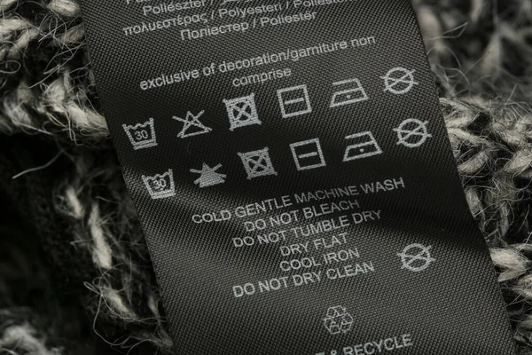 Fabric composition label, Washing instructions and recycling sign on black fabric label. Laundry tag on clothes.