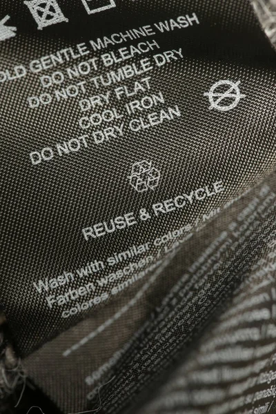 Fabric composition label, Washing instructions and recycling sign on black fabric label. Laundry tag on clothes.