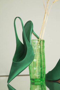 Yeşil saten topukluların yaratıcı stüdyo çekimi. Şık sivri uçlu, ürün fotoğrafçılığı.