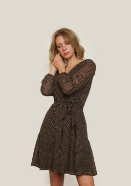 Boho tarzında kahverengi desenli elbiseli genç bir kadının stüdyo fotoğrafları.