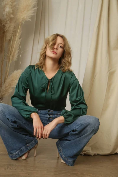 穿着松绿色丝绸衬衫和宽松牛仔裤的年轻女模特的摄影棚照片系列 — 图库照片