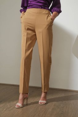 Bej renkli, şık, lüks pantolonlar giyen bir kadın model. Stüdyo çekimi.