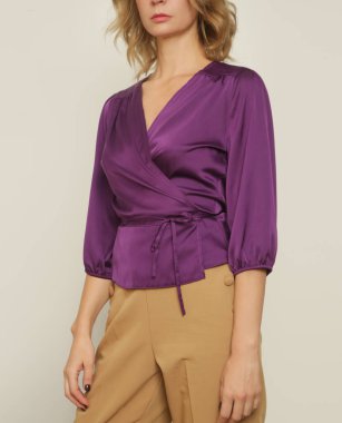 Stüdyo fotoğrafları. Menekşe ipek saten bluz giyen genç bir kadın model.