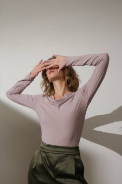 Dar yapışkan uzun kollu üst ve geniş yeşil saten pantolon giyen kadın model. Klasik, basit, rahat ama modaya uygun. Stüdyo çekimi.