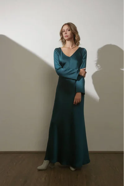 Serie of studio photos of young female model wearing maxi green silk dress with long sleeves