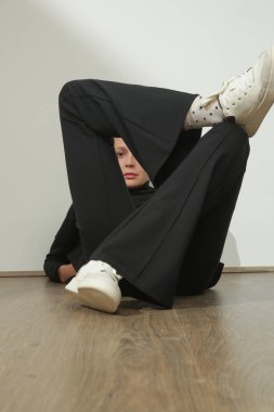 Stüdyoda çekilen siyah, rahat, balıkçı yaka kazak ve alevli pantolonlar giyen genç kadın modelin fotoğrafları..