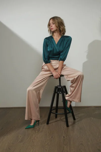 穿着丝绸缎子经典服装 翡翠绿色紧身衣和宽腿米色长裤的年轻女模特的摄影棚照片系列 — 图库照片