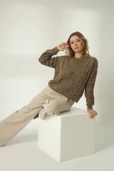 穿着棕色冬季毛衣和米色宽裤的年轻女子的时尚肖像 白色背景 — 图库照片