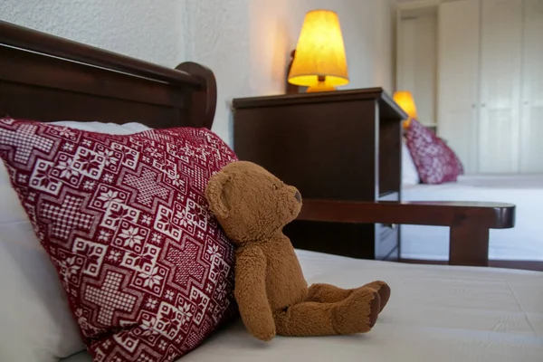 ベッドの上に赤いパターン枕と茶色のテディベアとレトロなベッドルームスタイル ストックフォト