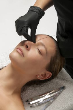 Mikrobleing kaş ölçüsü. Kozmetik uzmanı mükemmel şekilli kaşlar için kalem ve ipliklerle işaretler yapar. Profesyonel makyaj ve yüz bakımı. Kalıcı makyaj, kaş dövmesi.. 