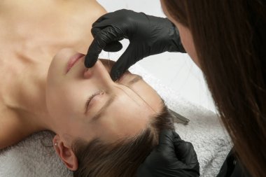 Mikrobleing kaş ölçüsü. Kozmetik uzmanı mükemmel şekilli kaşlar için kalem ve ipliklerle işaretler yapar. Profesyonel makyaj ve yüz bakımı. Kalıcı makyaj, kaş dövmesi.. 