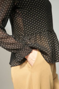 Stüdyoda çekilen zarif bluz ve bej pantolonlu genç bayan modelin ciddi fotoğrafları.