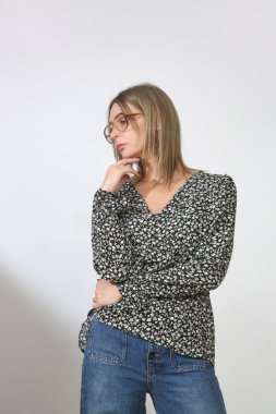 Stüdyoda çekilen zarif bluz ve rahat kot pantolonlu genç kadın fotoğraflarının serisi.