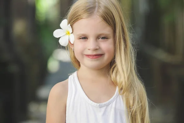 可爱的5岁小女孩的户外肖像画 一头美丽的金黄色长发 耳后挂着乳白色的花 热带度假的概念 — 图库照片