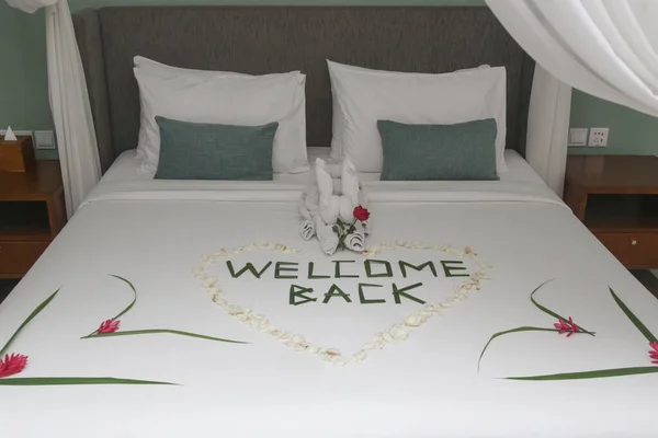 Welcome Back flowers and towels arrangement on the bed in luxury hotel on arrival.