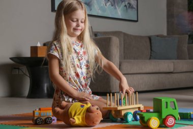 Adorable little girl playing with wooden toys at home