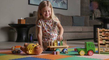 Adorable little girl playing with wooden toys at home