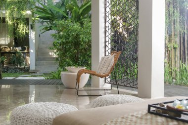 Half opened lounge area with all natural materials made furniture, rattan chairs with greenery behind