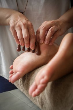 Müşteri ahşap uçlu masaj çubuğuyla akubasınçlı refleksoloji tedavisi görüyor. Doğal tıp, refleksoloji, akupunktur ayak masaj aleti enerji akış noktalarını bastırır.
