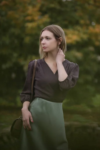 秋の季節に公園で緑の絹のサテンのスカートと茶色のブラウスの女性の屋外の肖像画 — ストック写真