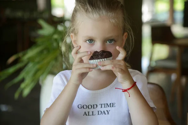 可愛いです5歳の女の子食べるチョコレートマフィンでザレストラン ロイヤリティフリーのストック画像