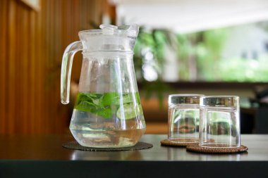 Detox water made of cucumber, lime and mint leaves in jug in the lounge area