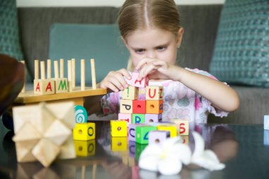 Adorable little girl playing with wooden toys at home