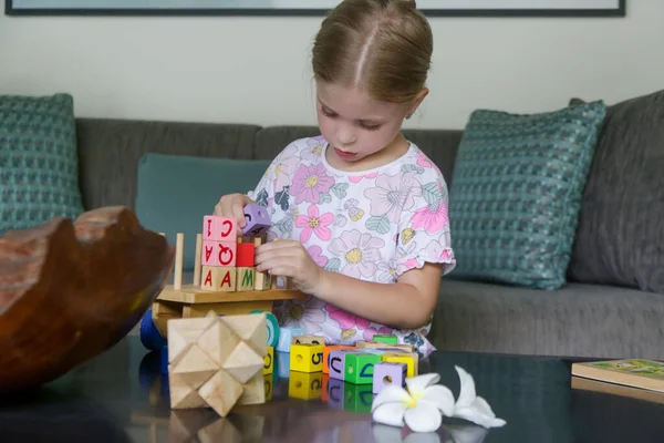 Adorable little girl playing with wooden toys at home