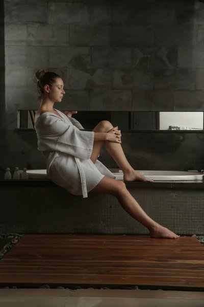 stock image Young woman in the bathroom wearing a robe getting ready to take a bath in the tub, wellbeing body care and beauty concept, spa weekend