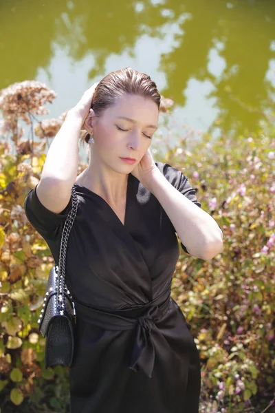 美丽的公园里穿着雅致典雅的黑色连衣裙的女人的户外肖像 秋季时装系列 — 图库照片