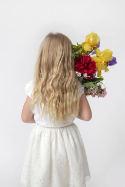 Stüdyo portresi. Güzel küçük bir kız. Elinde çeşitli çiçeklerden büyük renkli bir buket tutuyor..